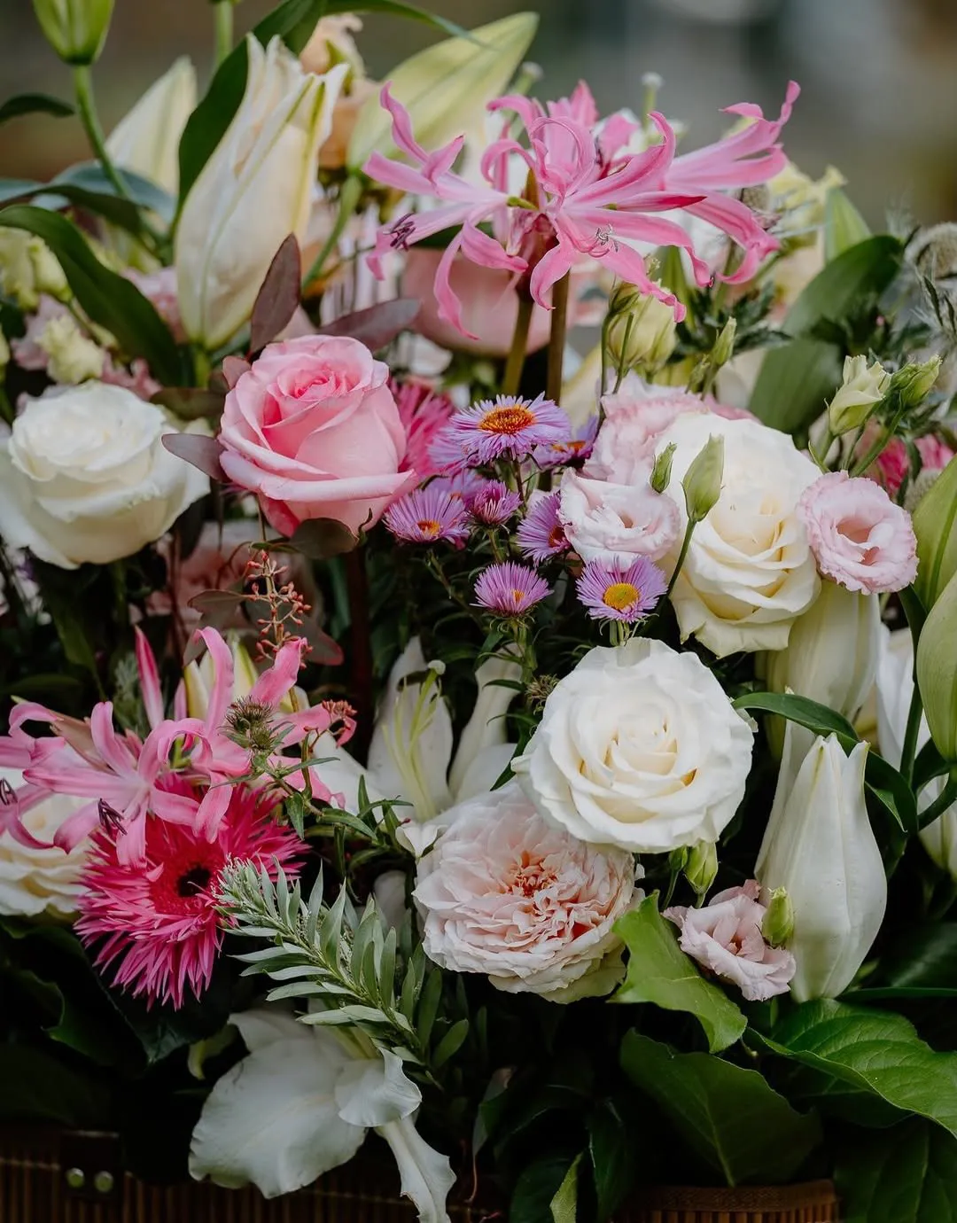 Svētku ziedi: baltas un rozā rozes, nerīnes, gerbera un asteres